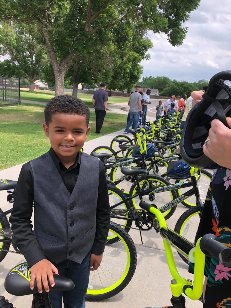 Children smiling for photo in front of black and green bikes